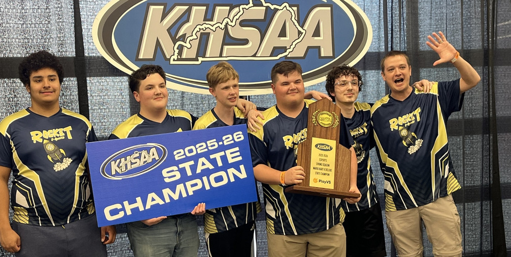 Shelby County High School esports players and their coach with a 2025–26 state championship banner and trophy.