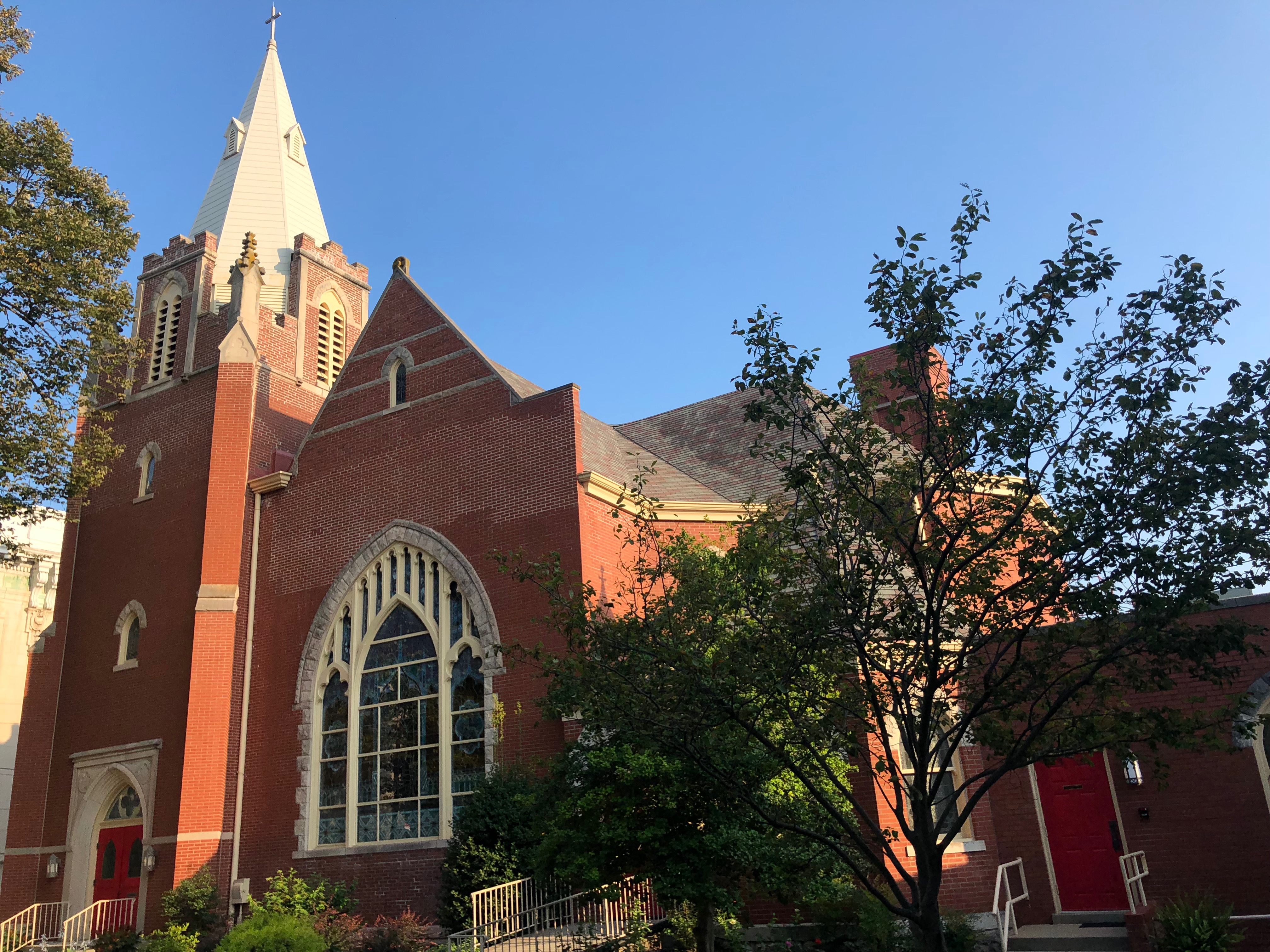 Centenary United Methodist Church’s red-brick sanctuary and white steeple in downtown Shelbyville, photographed in daylight.