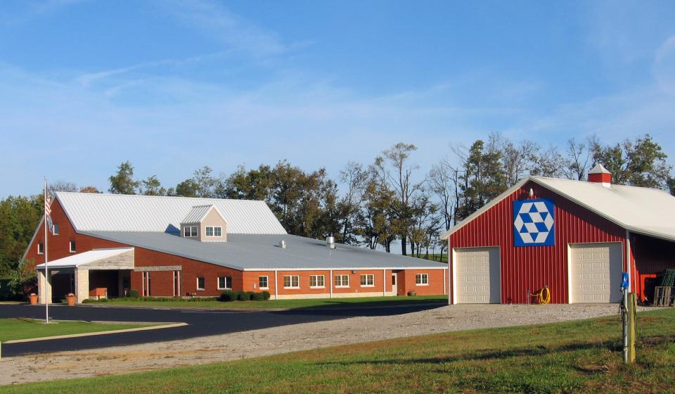 The red-brick Shelby County Extension building beside a red barn displaying a quilt block.